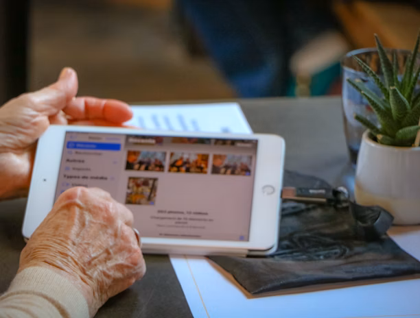 Idosa segura um tablet enquanto acessa depoimentos, simbolizando autonomia digital e confiança no cuidado da Dra. Kátia Colombo.